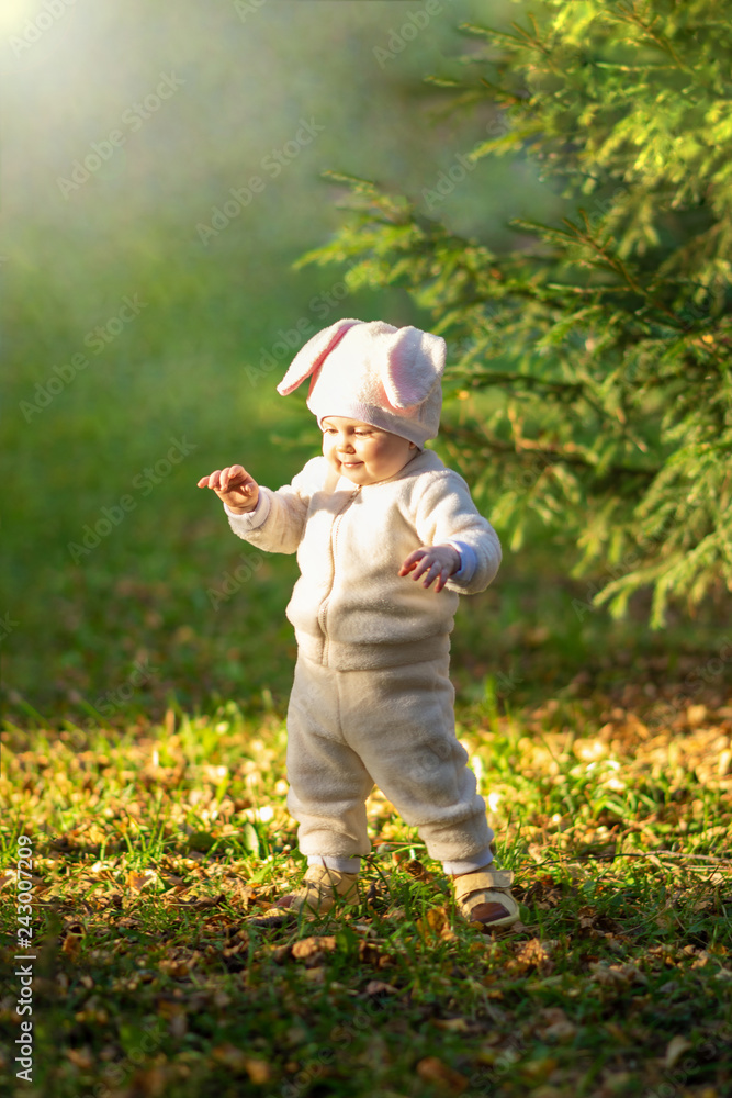 Small girl in bunny suit standing against sunlight in forest. Small girl in bunny suit standing against sunlight in forest.