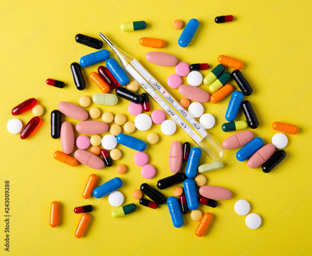 Pills capsules thermometer medicine health on yellow background top view, medical pharmacy concept Pills capsules thermometer medicine health on yellow background top view, medical pharmacy concept
