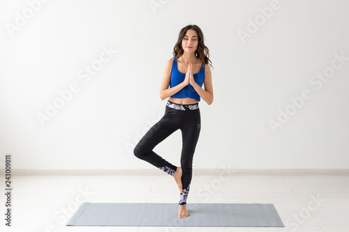 Yoga, sport, relax and people concept - young woman practicing yoga indoors