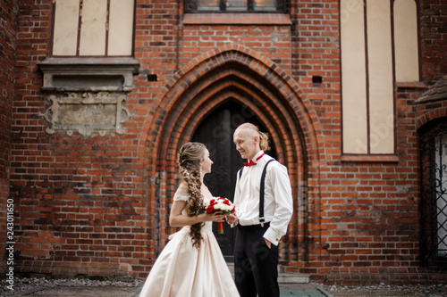 Young stylish married couple standing and smiling in the background of old building arch