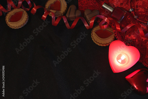 Valentine’s Day style background. Free space for text. Red and black still life. Love and passion. Sweets, candles and red lingerie