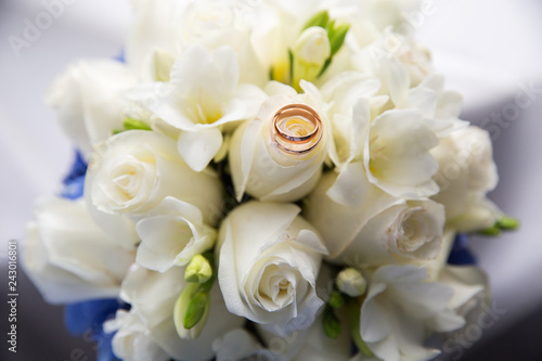 A pair of wedding rings on a bouquet of white roses  close up shot