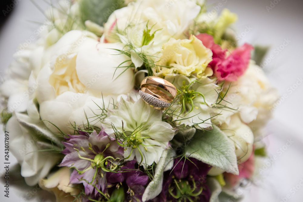 A pair of wedding gold rings on a bouquet of colorful flowers, close up shot A pair of wedding gold rings on a bouquet of colorful flowers, close up shot