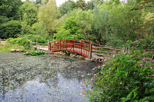 arched wooden footbridge over a large pond on a woodland trail