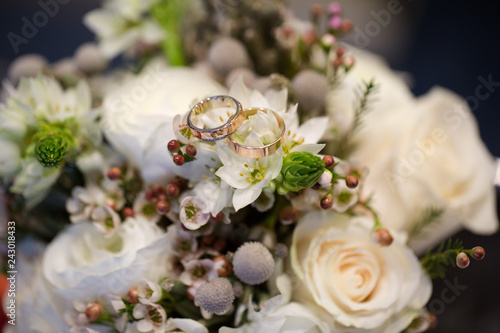 A pair of wedding rings on a bouquet of white flowers  close up shot