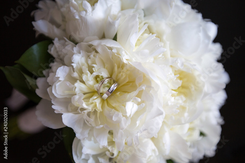 A pair of wedding rings on a bouquet of white flowers, close up shot © FrameSculptor