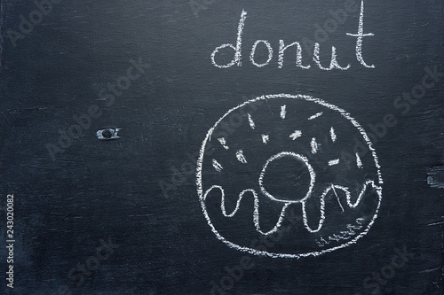 Donut drawing in chalk on a black board, copy space