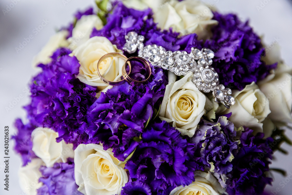 A pair of wedding gold rings on a bouquet of colorful flowers, close up shot A pair of wedding gold rings on a bouquet of colorful flowers, close up shot
