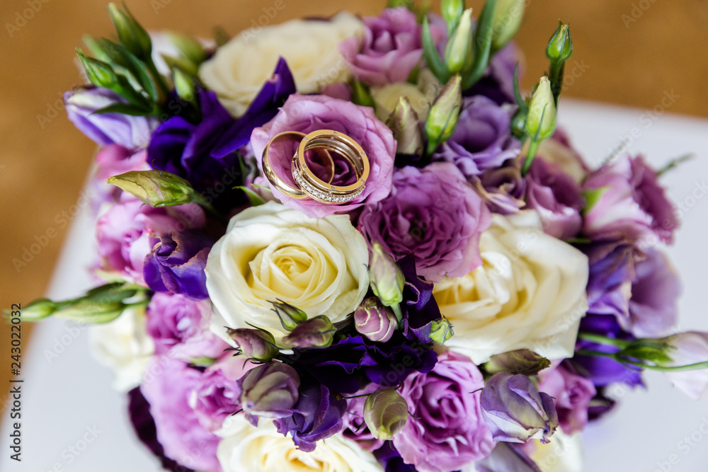 A pair of wedding gold rings on a bouquet of colorful flowers, close up shot A pair of wedding gold rings on a bouquet of colorful flowers, close up shot