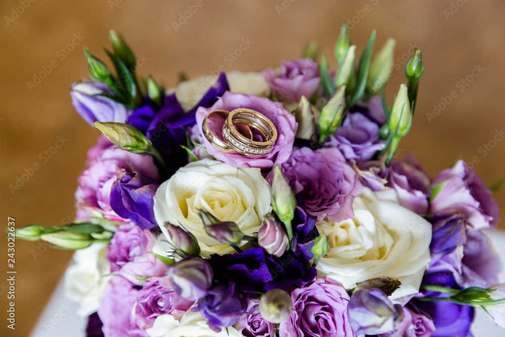 A pair of wedding gold rings on a bouquet of colorful flowers, close up shot A pair of wedding gold rings on a bouquet of colorful flowers, close up shot