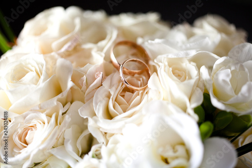 A pair of wedding rings on a bouquet of white flowers, close up shot