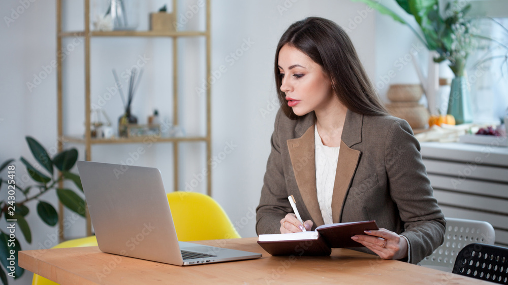 A charming business brunette with glasses plans a business project, make notes in the planner. A charming business brunette with glasses plans a business project, make notes in the planner.