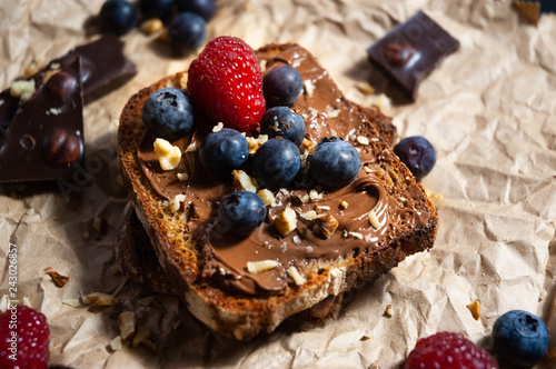  Delicious chocolate bread toast with chocolate spread and bluberry and nuts toppings on rustic paper with black background