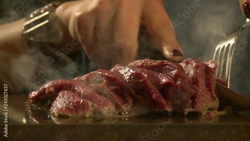 The girl in the restaurant prepares meat on a hot stone photo