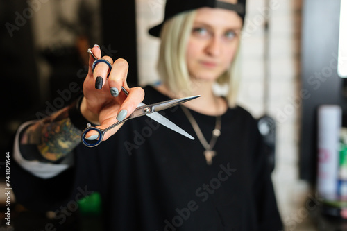 Girl sit on the chair and hold scissors in Barber Shop. - Image