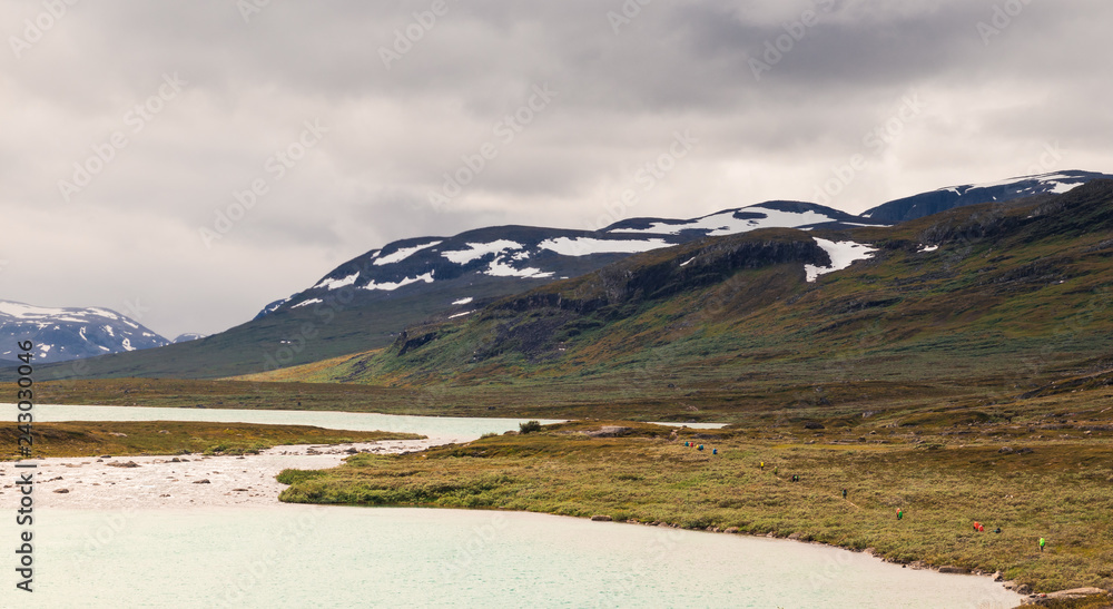 Row of people walking a trail during the hike of Kungsleden (Kings path) in northern Sweden. 