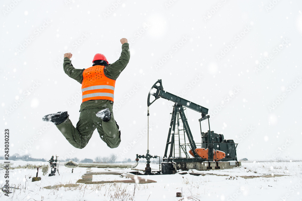 Φωτογραφία Happy oil and gas refinery worker jumping in front of the pump jack in oil and natural gas industry field