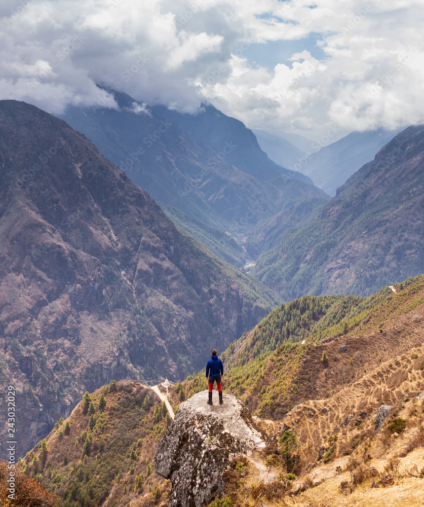 Person standing on a rock looking out over a valley in Nepal during the Everest Base Camp Trek.