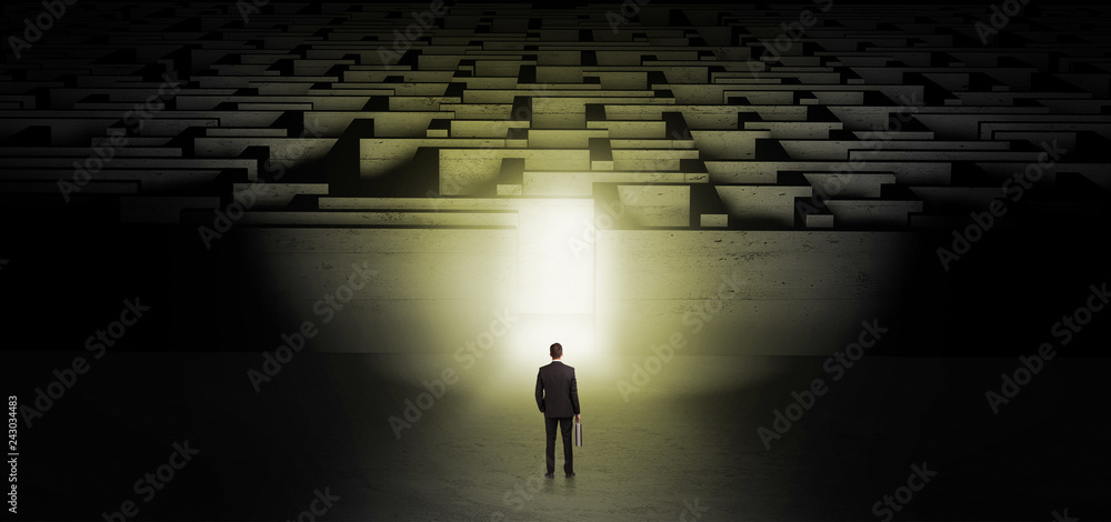 Businessman getting ready to enter the dark labyrinth with illuminated door
