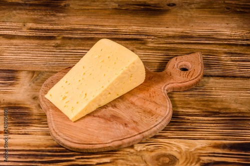 Cutting board with piece of cheese on wooden table