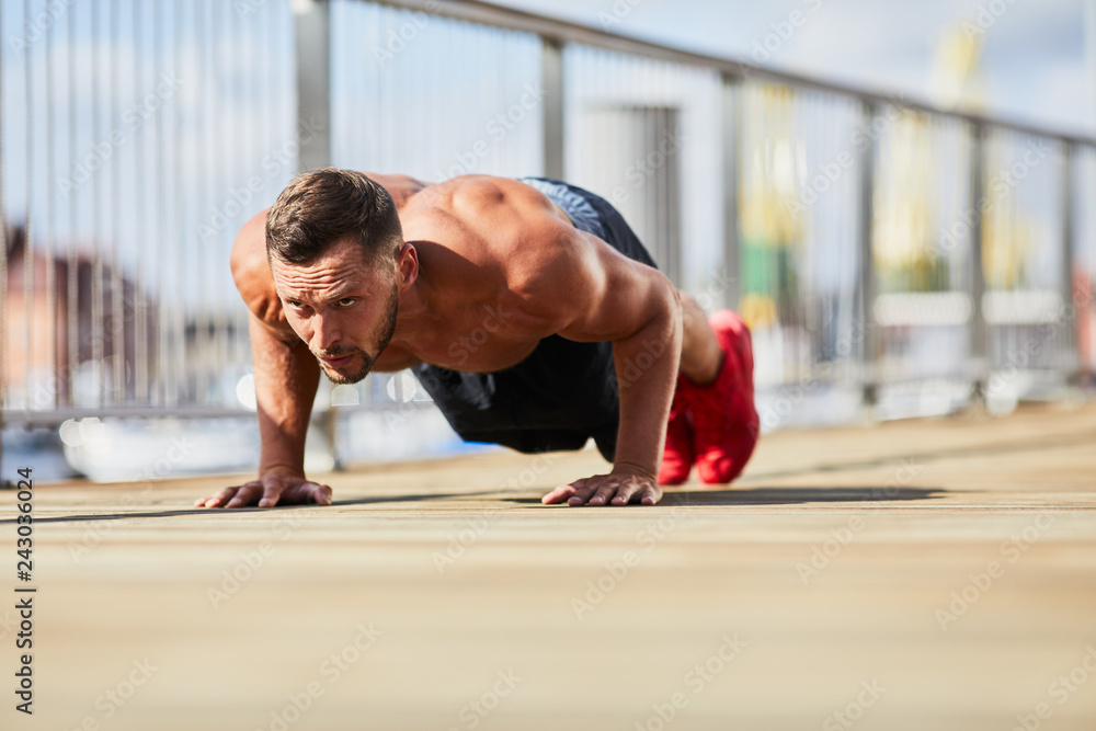 Fototapeta premium Athletic man doing pushup exercise outdoors