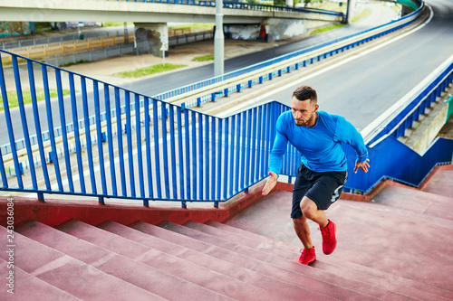 Athletic man doing interval training running on stairs in urban setting