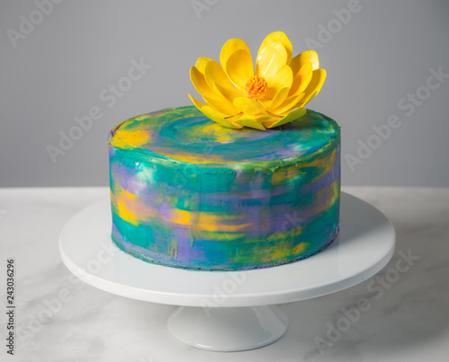 Horizontal waterlily themed birthday cake on a stand with a yellow flower on top. 