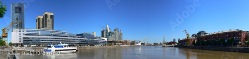 Panorama of the Puerto Madero port area of Buenos Aires in Argentina. Tourist spot with the famous Puente de la Mujer - Woman's bridge - among the old warehouses and new high rise buildings.