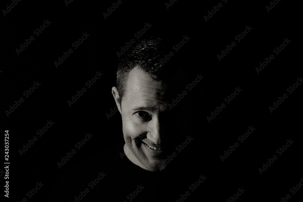 Face of a shy smiling man in black and white low key portrait Face of a shy smiling man in black and white low key portrait