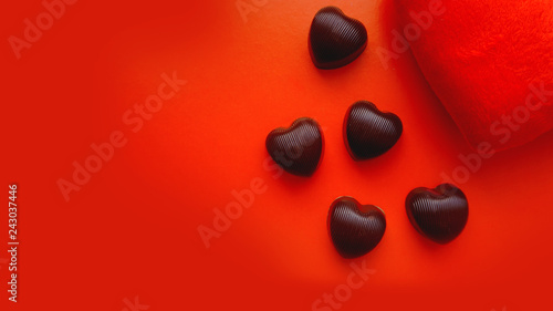 Valentines day background with soft toy heart and chocolates on red background