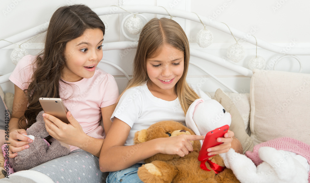 It cant be true. Happy little children with mobile phone. Merry Christmas and Happy New Year greetings. Little girls use smartphone in bed. Ordering gifts for Christmas and New Year by phone It cant be true. Happy little children with mobile phone. Merry Christmas and Happy New Year greetings. Little girls use smartphone in bed. Ordering gifts for Christmas and New Year by phone