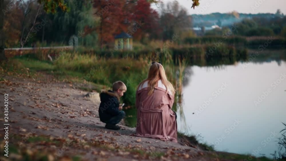 Picturesque autumn bokeh. Colorful landscape ,cute child boy with parent mother plays near the lake. Good childhood memories. Picturesque autumn bokeh. Colorful landscape ,cute child boy with parent mother plays near the lake. Good childhood memories.