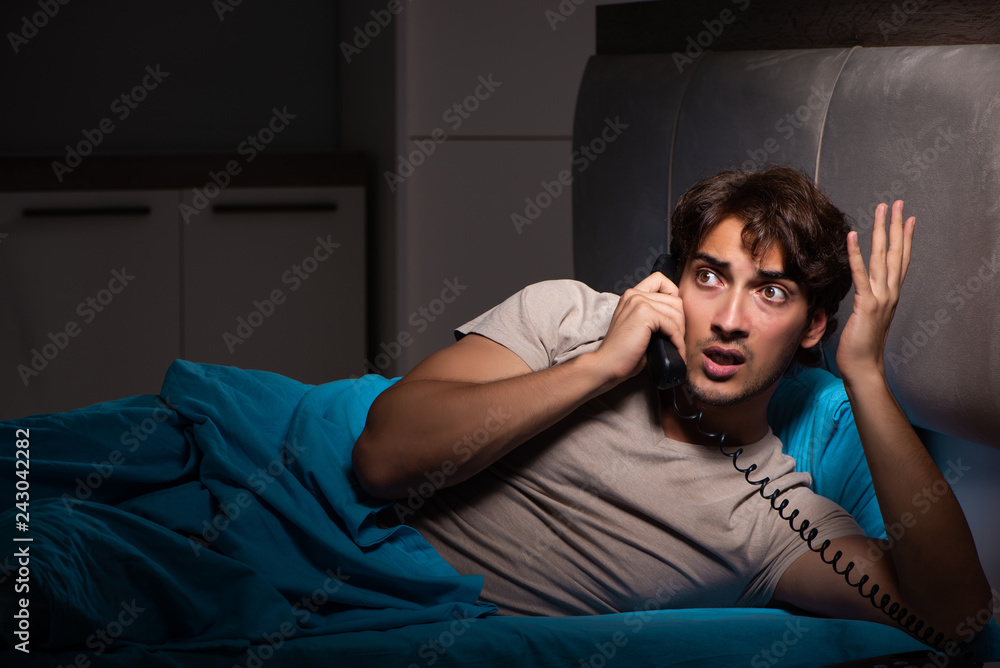 Young man talking on phone in bed Young man talking on phone in bed