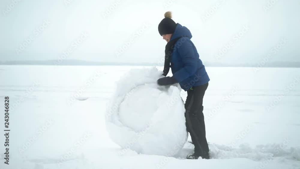 boy rolls big snow ball for snowman in winter. boy rolls big snow ball for snowman in winter.