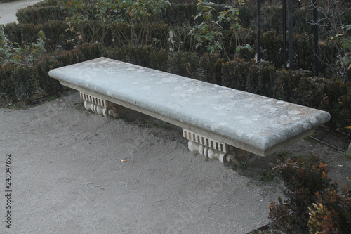 Gray stone bench, surrounded by vegetation. photo taken with daylight