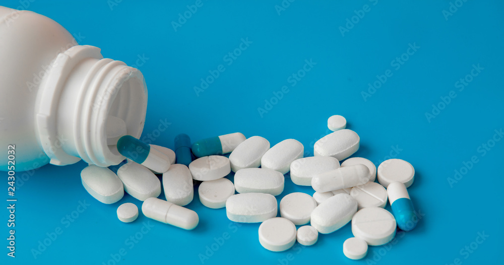 Scattered white pills on blue table. Mock up for special offers as advertising, web background or other ideas. Medical, pharmacy and healthcare concept. Copy space. Empty place for text or logo Scattered white pills on blue table. Mock up for special offers as advertising, web background or other ideas. Medical, pharmacy and healthcare concept. Copy space. Empty place for text or logo