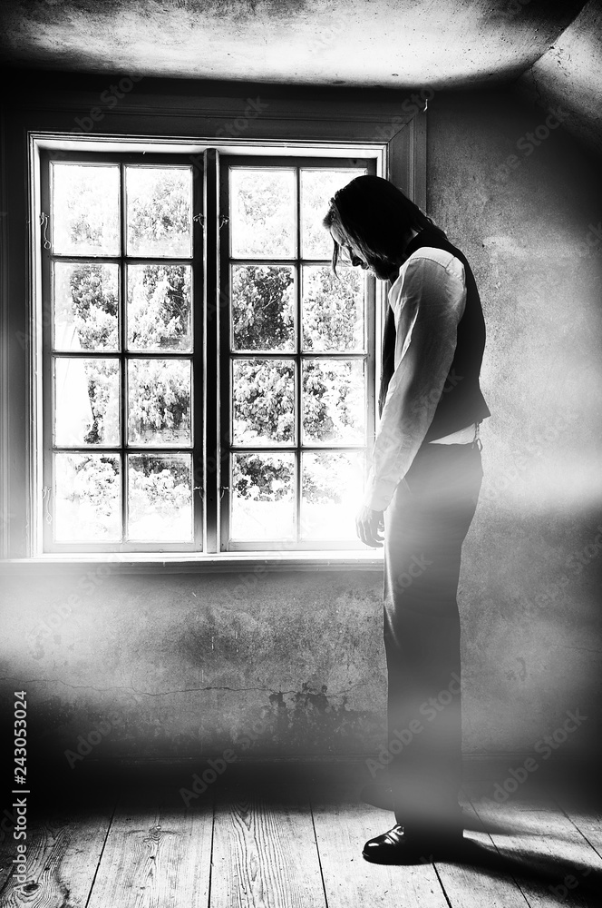 Fototapeta premium A sad man in front of window, grunge style