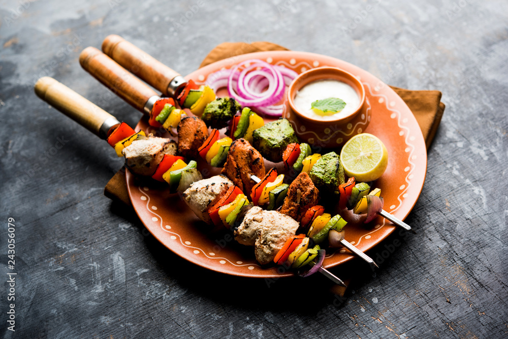 Chicken Hariyali kakab or Malai malai kebab served with skewers and yogurt dip in a plate. selective focus Chicken Hariyali kakab or Malai malai kebab served with skewers and yogurt dip in a plate. selective focus