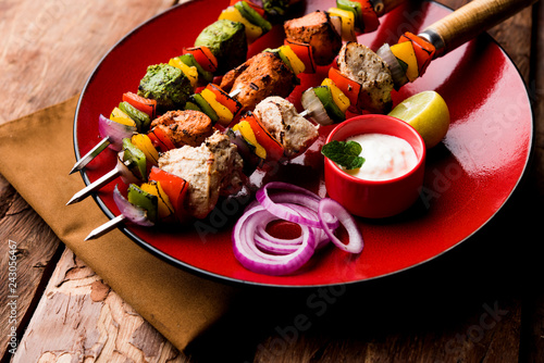 Chicken Hariyali kakab or Malai malai kebab served with skewers and yogurt dip in a plate. selective focus photo