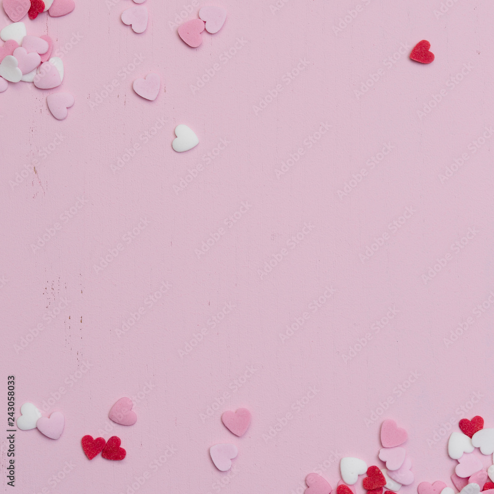 Square flatlay image for social media usage with many tiny heart-shaped sugar sprinkles in red, white and pink with space for copy text or love letter message for Valentine's Day on February 14th