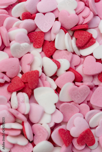 Close up macro shot of hundreds of small heart-shaped sugar sprinkles in red, pink and white for Valentine's day card, symbol for love, emotion or romantic feelings as background or wallpaper image
