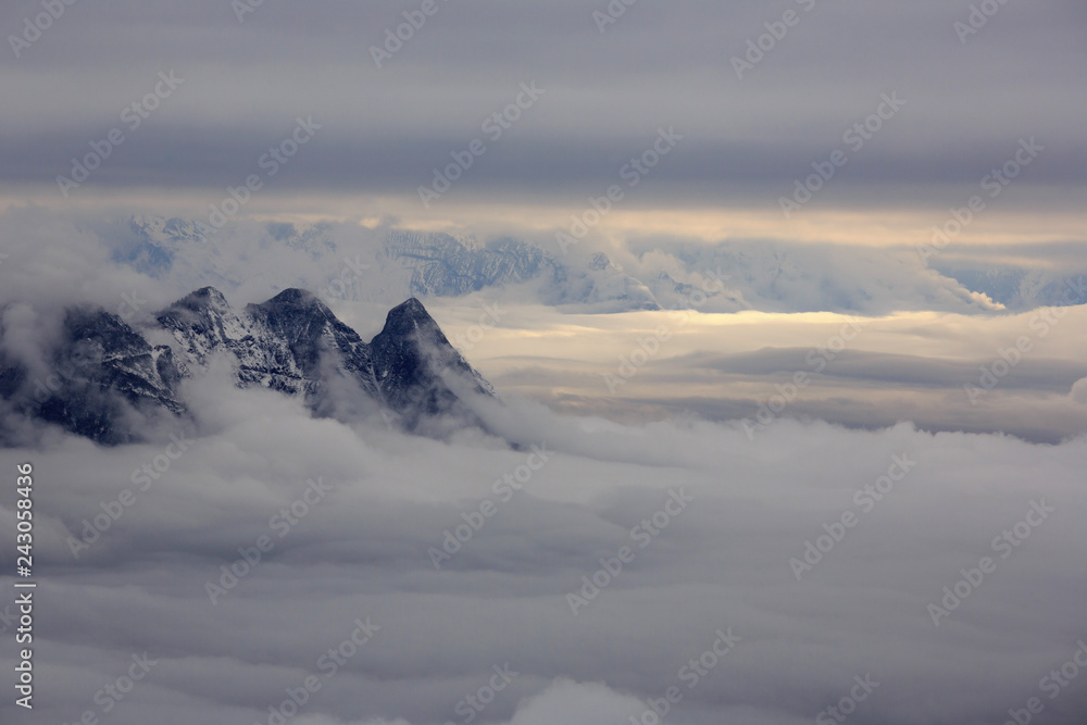 Abstract landscape photograph, mountains shrouded in clouds. Fog floating between mountain peaks, Chinese mountains. Ridgeline, artistic minimalistic landscape image. peaceful nature background image