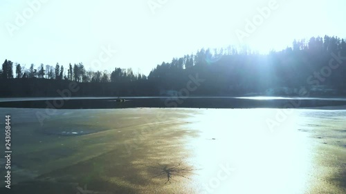 Aerial view of a frozen little Lake in Switzerland at a sunny winter Day with a fisher boat
