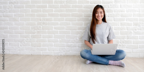 Young asian woman in casual style using laptop computer in white room background with copy space, people and technology, lifestyles
