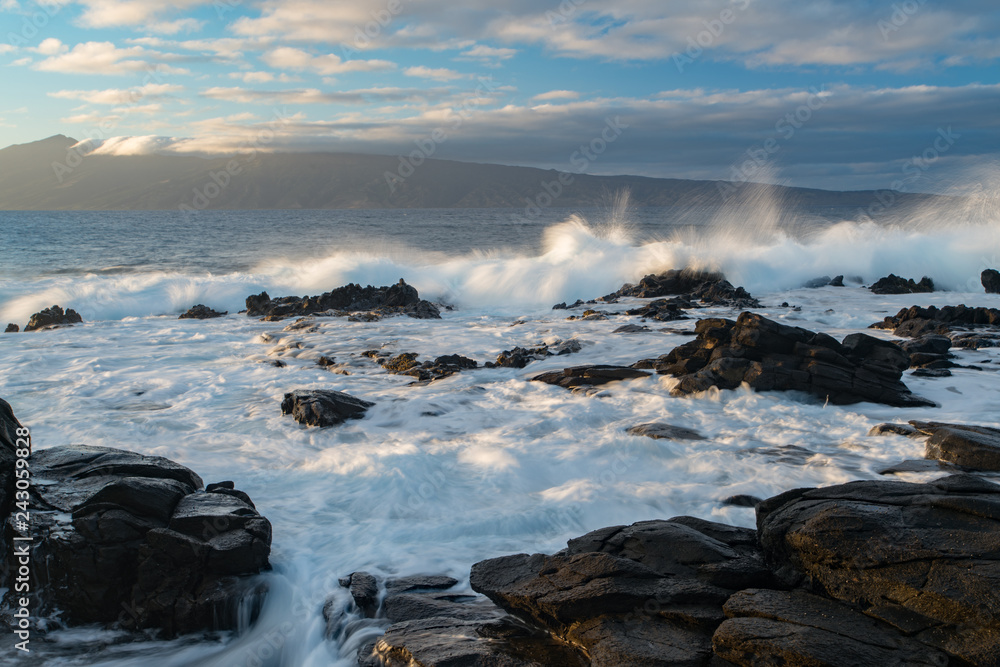 Waves breaking on a rocky shore just after a passing storm on the Hawaiian island of Maui at sunset.