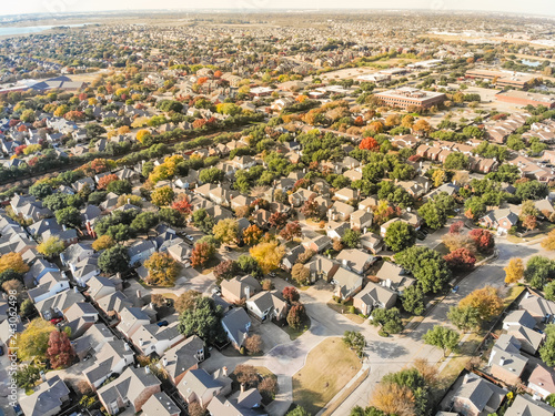 Aerial drone view urban sprawl in suburban Dallas  Texas during fall season with colorful leaves. Flyover subdivision with row of single-family detached houses and apartment complex