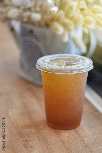 Lemon tea in plastic cup on counter bar table beside windows. Selective focus.