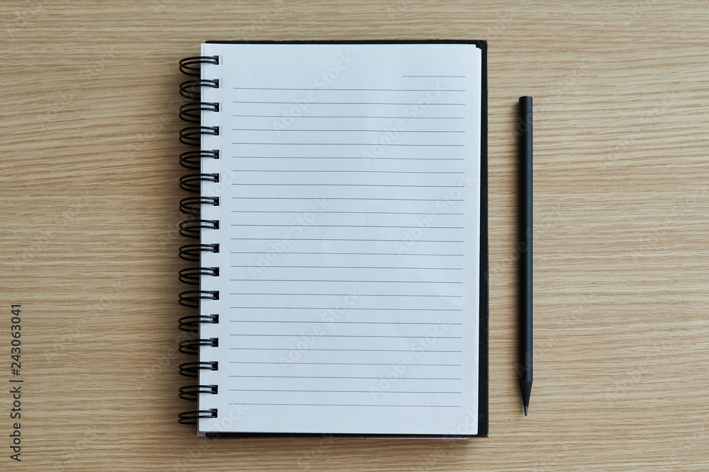 Top view close up of blank white diary book with black pencil on wood table. Selective focus. Top view, Flat lay. Top view close up of blank white diary book with black pencil on wood table. Selective focus. Top view, Flat lay.