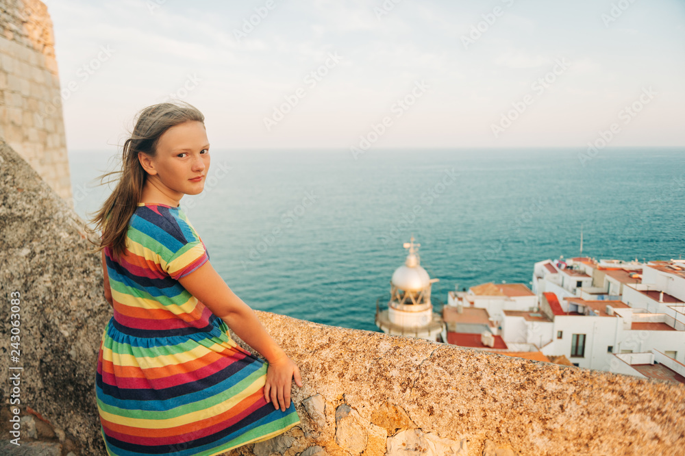 Little girl on the top of Peniscola, admiring amazing summer sunset, travel with children, wearing colorful dress