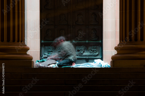 homeless man moves as he wakes on the steps of a city building
